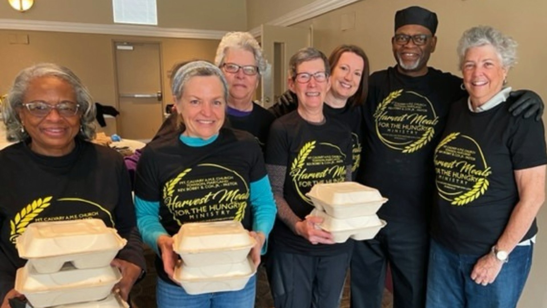 A group of individuals holding carry-out boxes for meals for the hungry